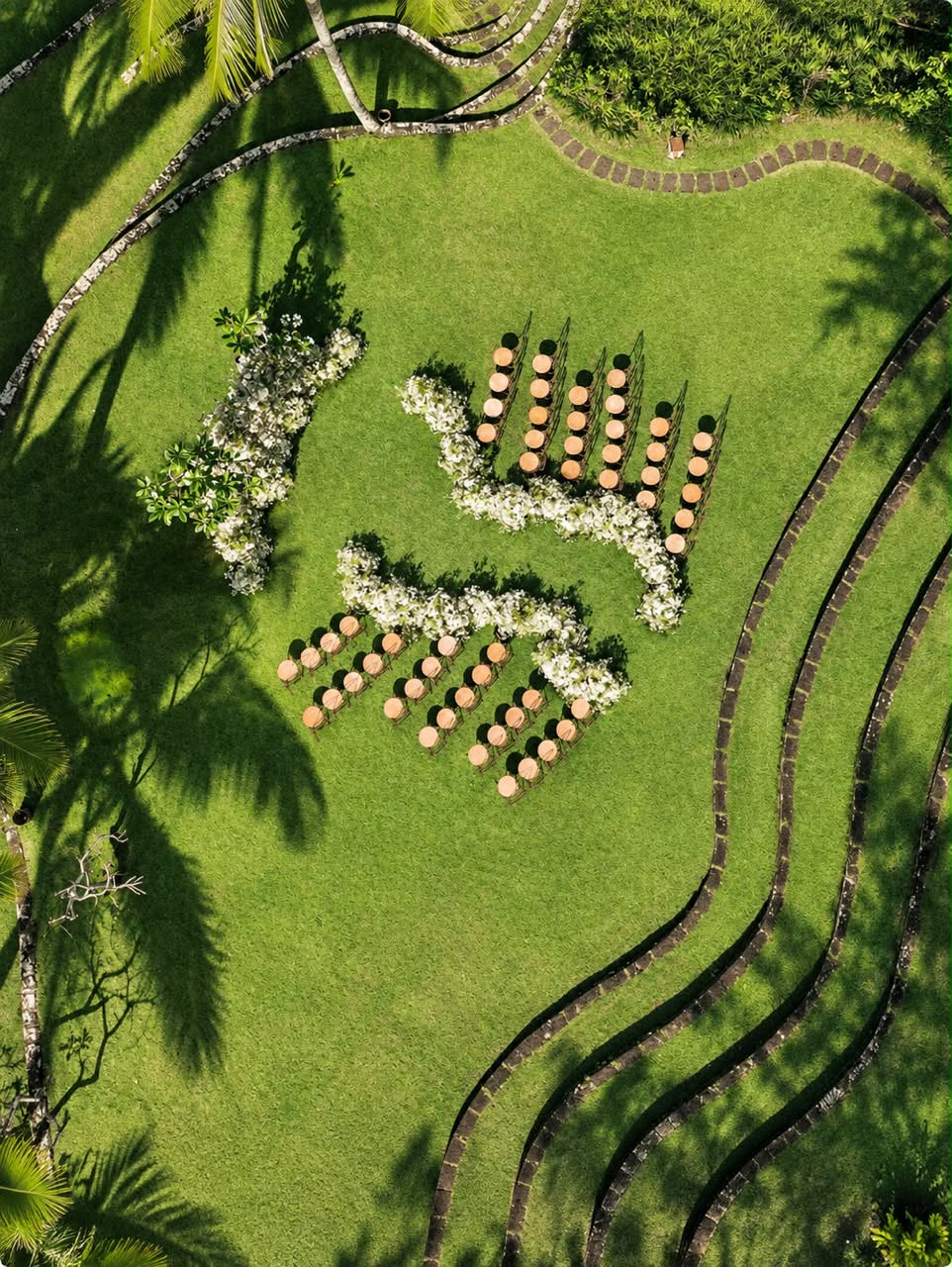 Palm shadows and white floral arrangements across a green Hawaiian lawn